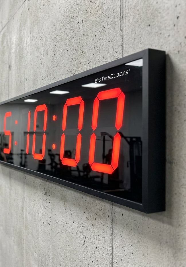 Digital clock with red digits on a concrete wall