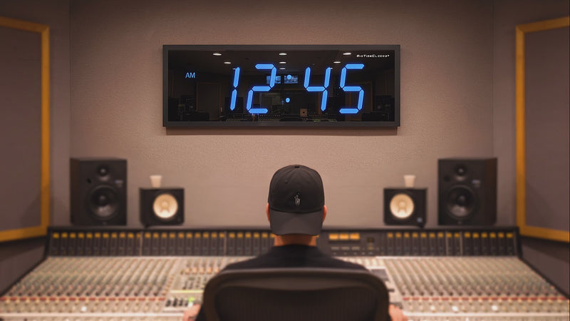 Sound engineer in recording studio with blue led BigTimeClocks digital clock on wall